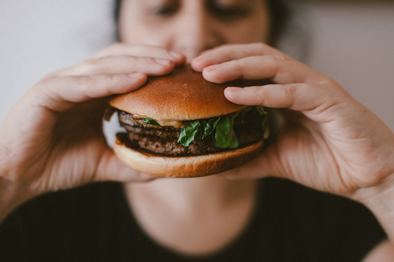 Delicious beef burger with fresh lettuce held by a womans hands, focus on the food.